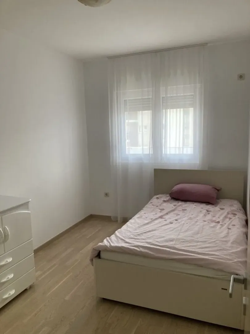 Bright and tidy bedroom with a bed and a dresser.