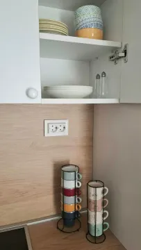 Detail of a kitchen cabinet with tableware and mugs on the countertop. - image 14