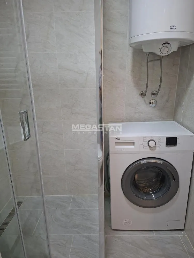 Bathroom with a shower cabin, washing machine, and water heater.