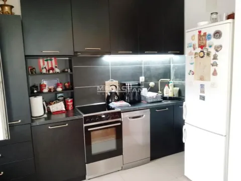 Kuhinja tamnih tonova opremljena šporetom, mašinom za pranje sudova i frižiderom. - image 7