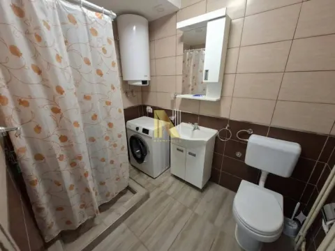 Compact bathroom with a shower enclosure, washbasin, washing machine, and toilet. - image 4