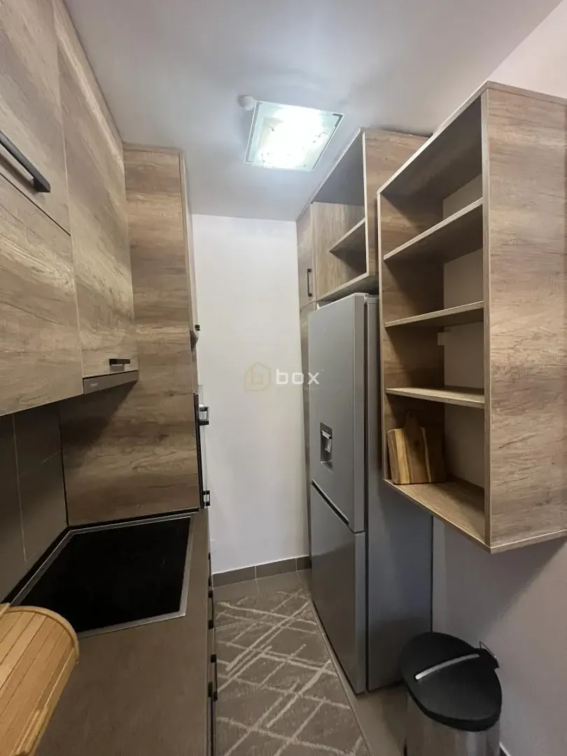 Small kitchen with wooden elements and a refrigerator.