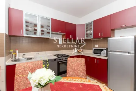 Kitchen with red cabinets, dining table and refrigerator. - image 3
