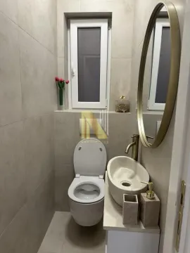 Manje kupatilo obloženo keramičkim pločicama sa toaletom, umivaonikom i okruglim ogledalom. - image 9