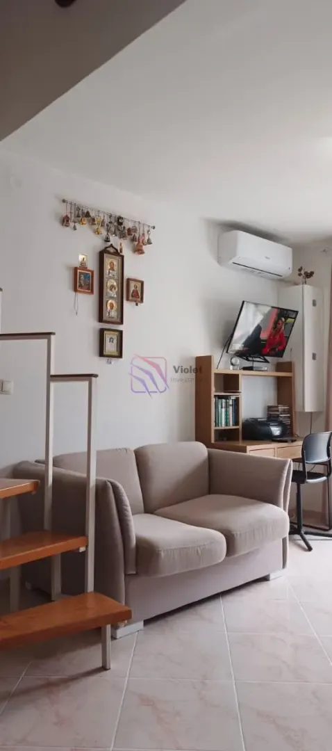 Dnevna soba sa kaučem, radnim stolom i stepeništem.