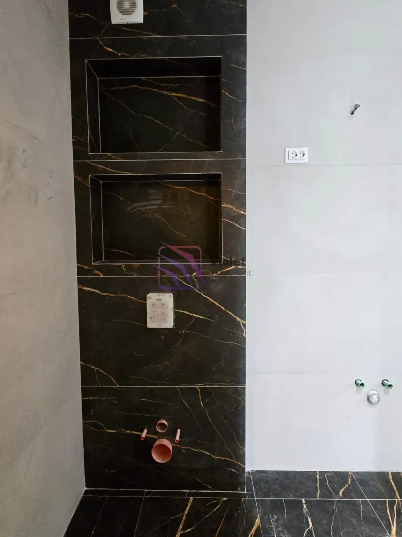 Kupatilo u fazi adaptacije sa keramičkim pločicama i pripremljenim instalacijama.