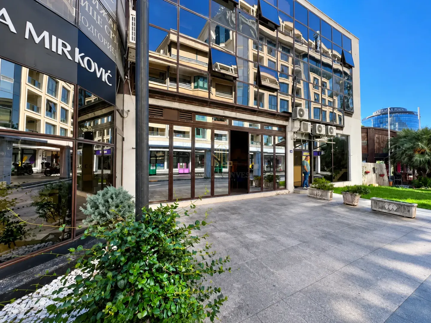 Exterior of a commercial building with large glass surfaces and a paved platform in front of the entrance.