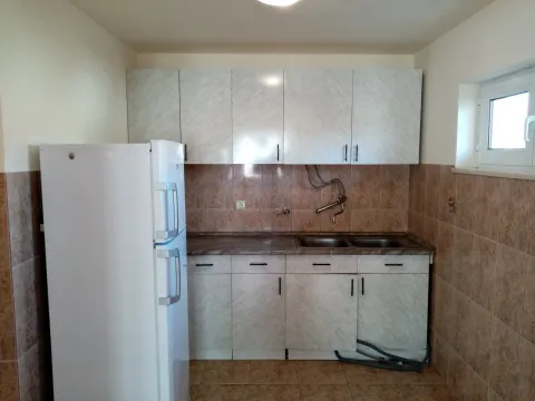 A simple kitchen with light cabinets, a refrigerator, and a double sink. - image 12