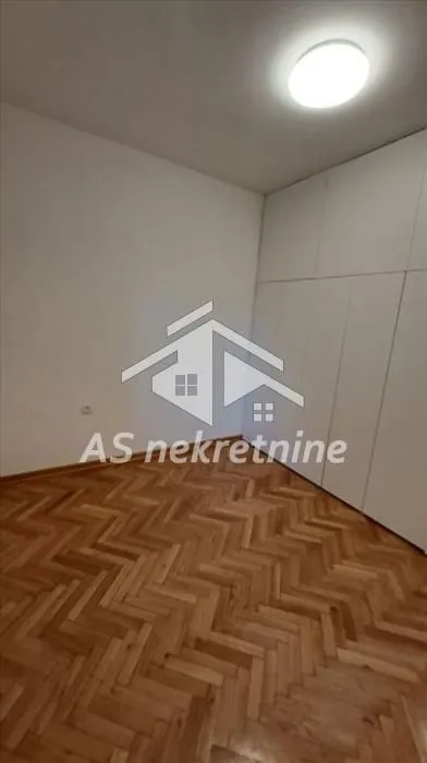Empty bedroom with a built-in wardrobe and parquet flooring.