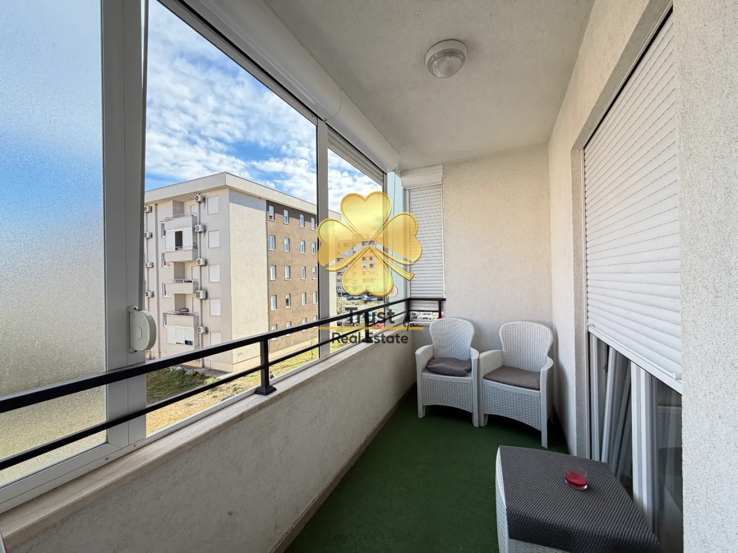 Enclosed balcony with seating furniture and a view of the building.