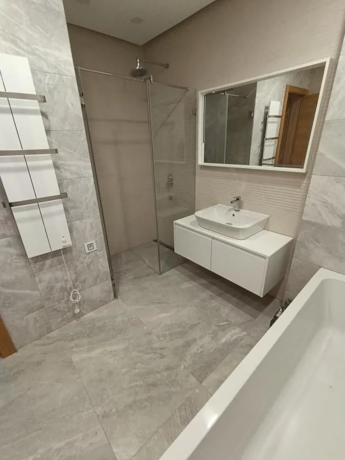 Modern bathroom with walk-in shower, bathtub, washbasin, and mirror.