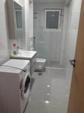 Modern bathroom with a walk-in shower, washbasin, and washing machine. - image 11
