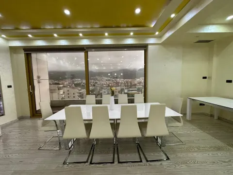 Spacious dining room with a large table, white chairs, and a city view. - image 4