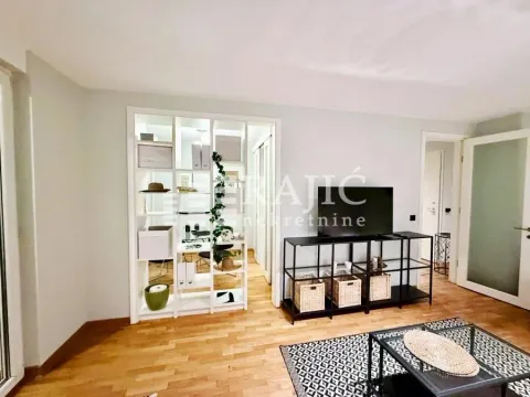 Living room with hardwood flooring and a partition shelving unit leading to a workspace. - image 2