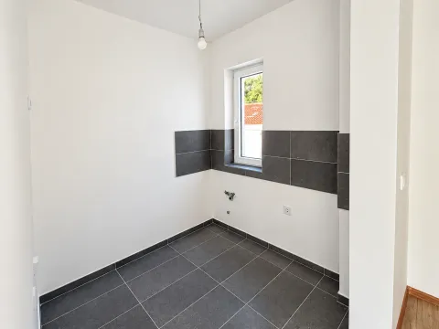 Prazna kuhinja sa tamnim podnim i zidnim pločicama i pripremljenim instalacijama. - image 8