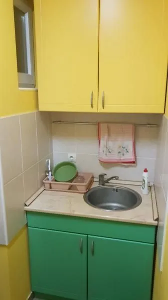Manja kuhinja sa žutim elementima i sudoperom.