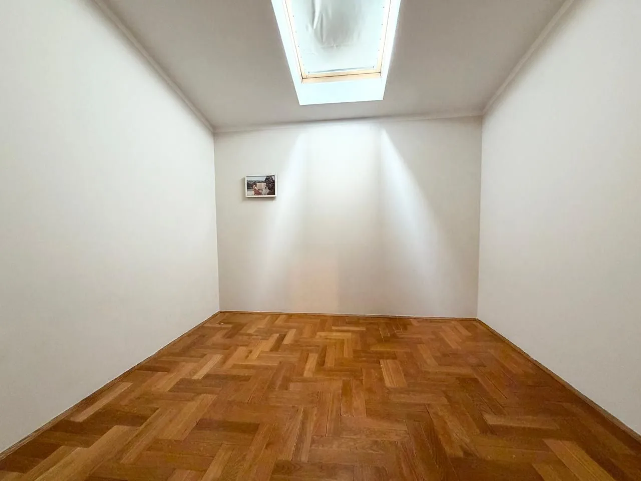 Prazna soba sa parketom i krovnim prozorom.