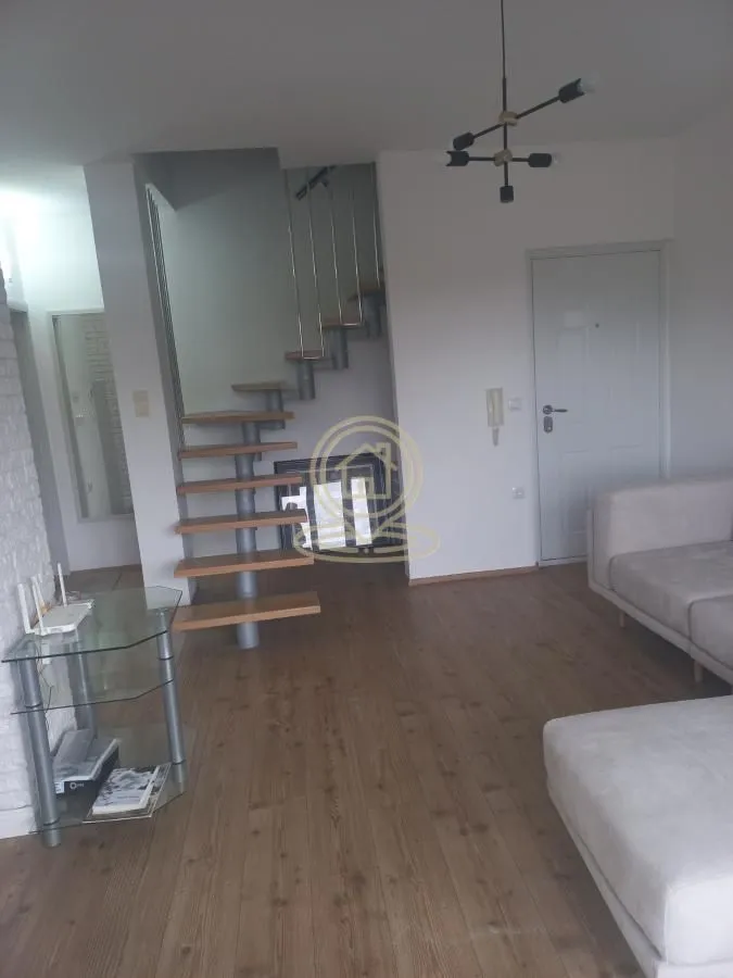 Living room with a sofa, staircase, and entrance door.