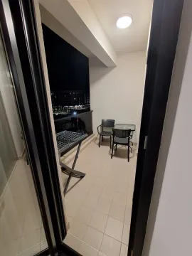 Covered balcony with patio furniture and a drying rack at night. - image 10