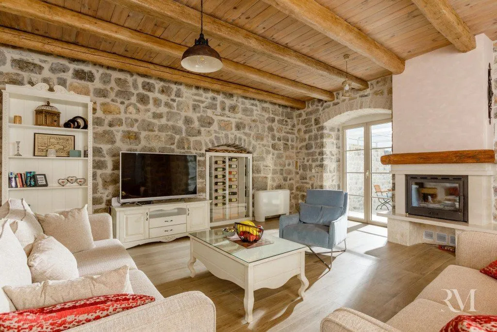 Living room with stone walls, wooden beams, and a fireplace.