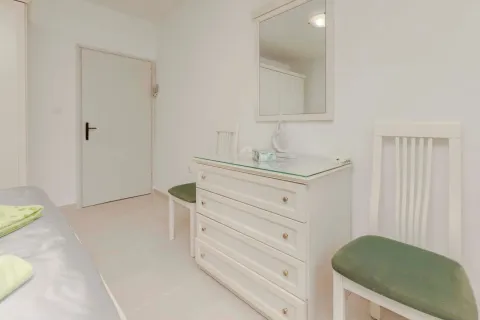 Bright bedroom with a white dresser, mirror, and chairs. - image 14