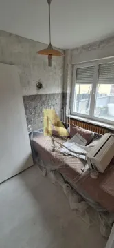 Manja soba sa krevetom prekrivenim zaštitnom folijom tokom renoviranja. - image 5