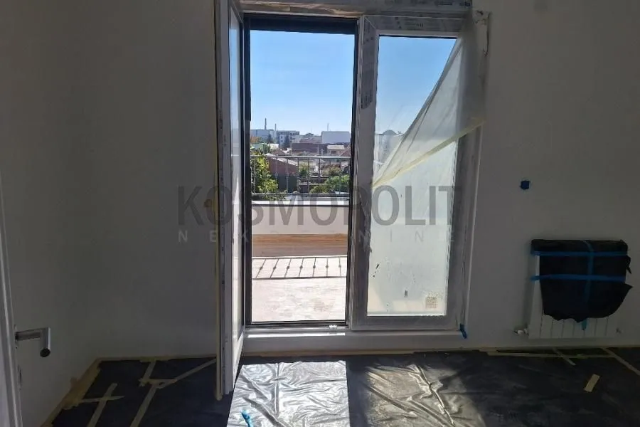 Prazna prostorija sa izlazom na balkon i zaštitnim folijama na podu.