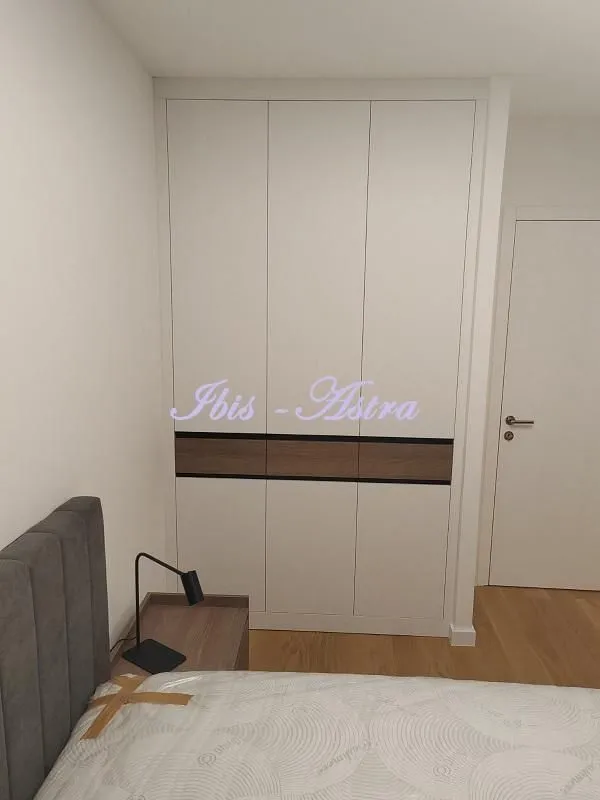 Bedroom with a bed, nightstand, and built-in wardrobe.