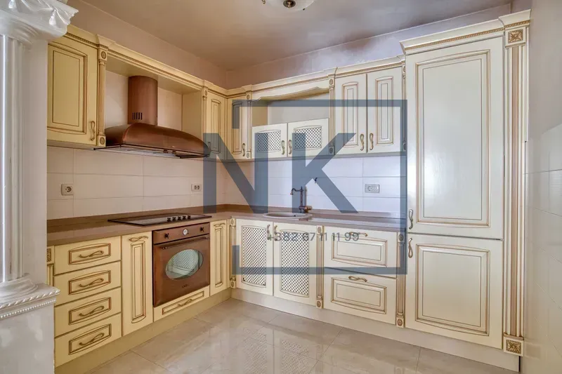 Kitchen with light classic-style cabinetry and built-in appliances.