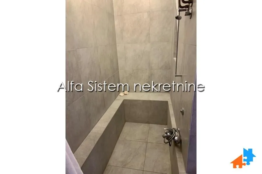 Kupatilo obloženo keramičkim pločicama sa ugradnom kadom.
