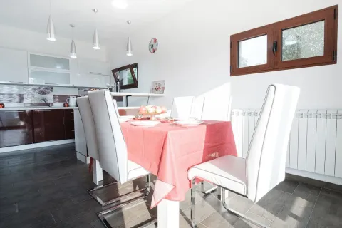 Modern kitchen with a dining area and white chairs. - image 15