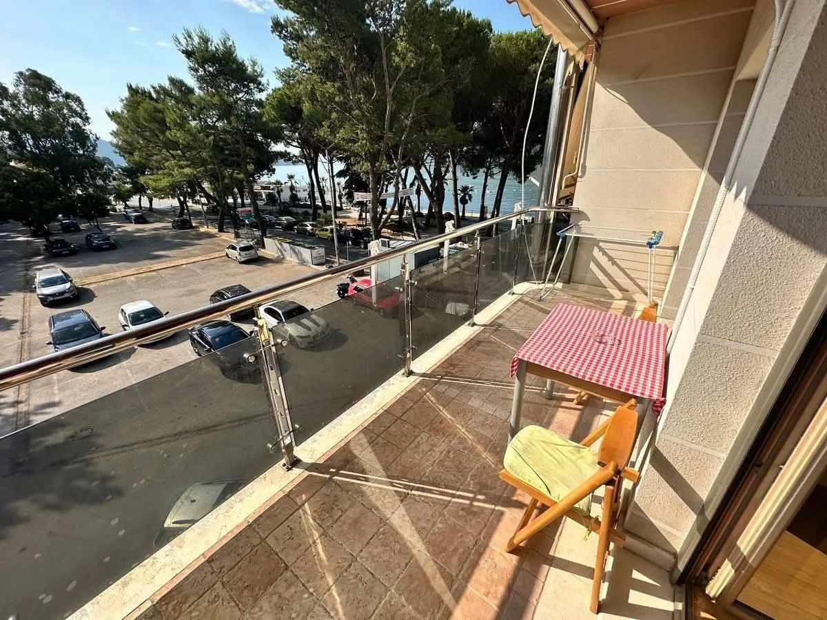 Namješten balkon sa stolom i pogledom na ulicu i drveće.