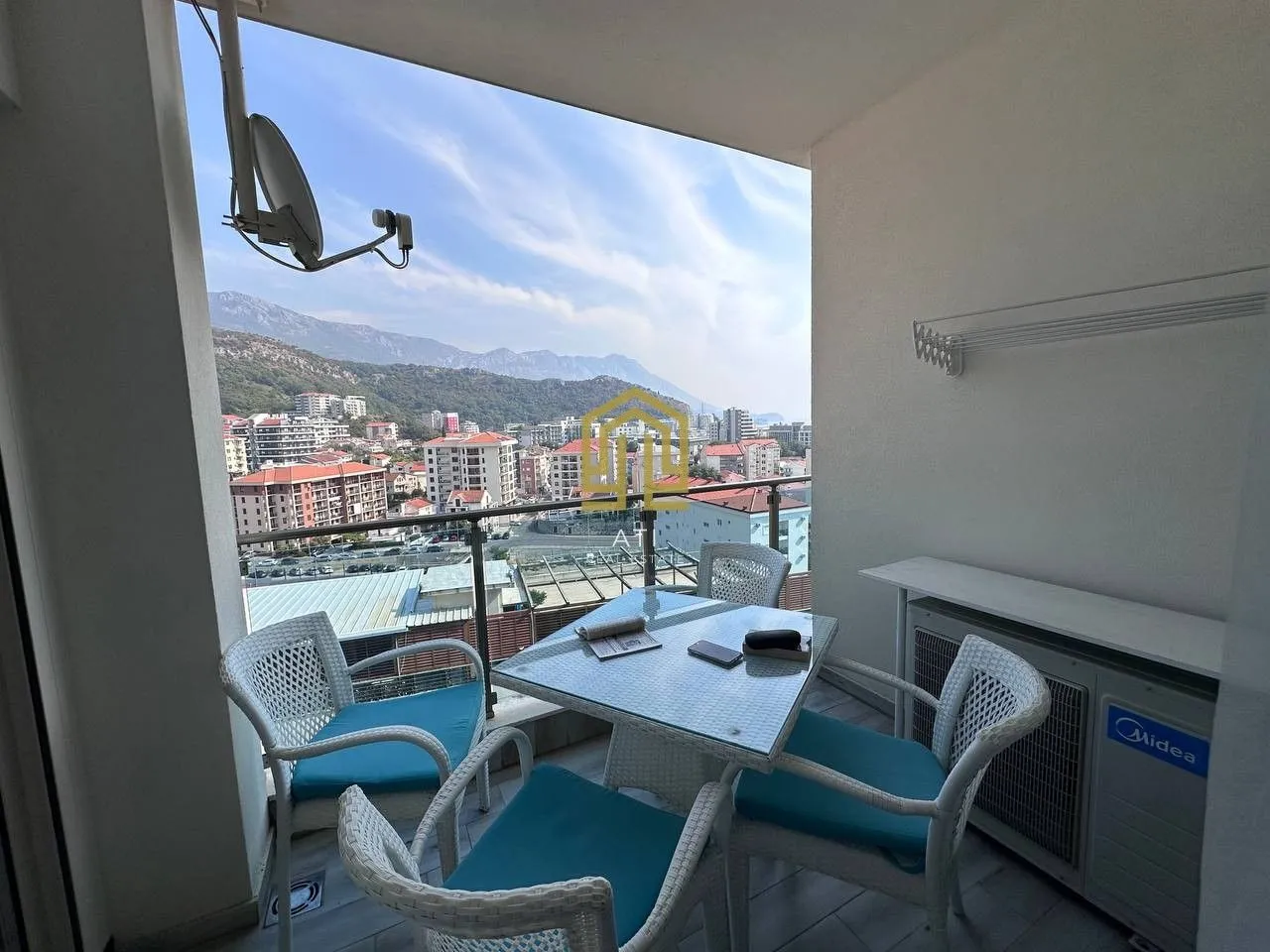 Furnished terrace with table, chairs and a view of the city and mountains.