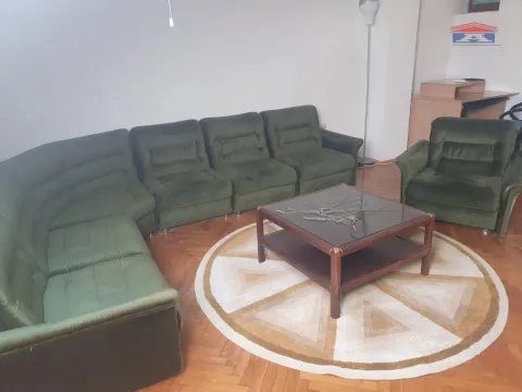 Dnevna soba sa zelenom ugaonom garniturom, foteljom i drvenim stočićem na parketu. - image 2