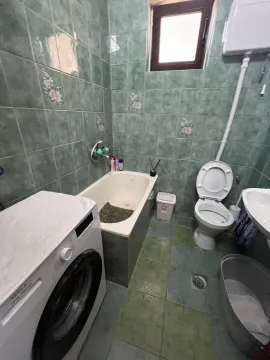 Kupatilo obloženo zelenim pločicama sa kadom, wc šoljom, umivaonikom i mašinom za veš. - image 4