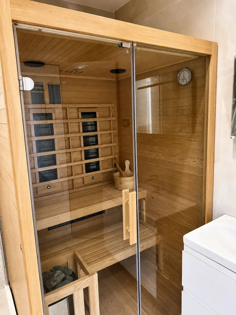 Wooden sauna in the bathroom with glass doors.