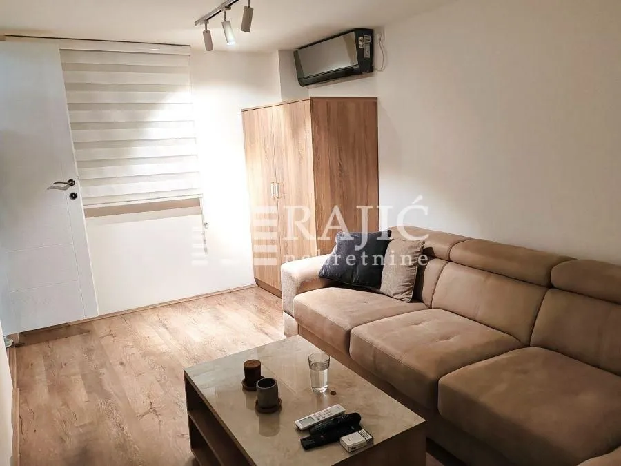 Furnished living room with sofa and wooden wardrobe.