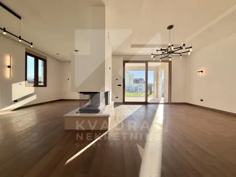 Spacious empty living room with a central fireplace and hardwood flooring. - image 23
