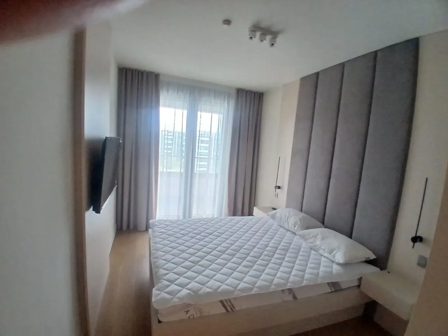 Moderna spavaća soba sa bračnim krevetom i tapaciranim uzglavljem.