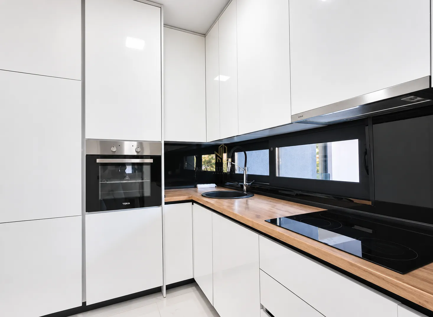 Modern white kitchen with a wooden countertop and built-in oven.