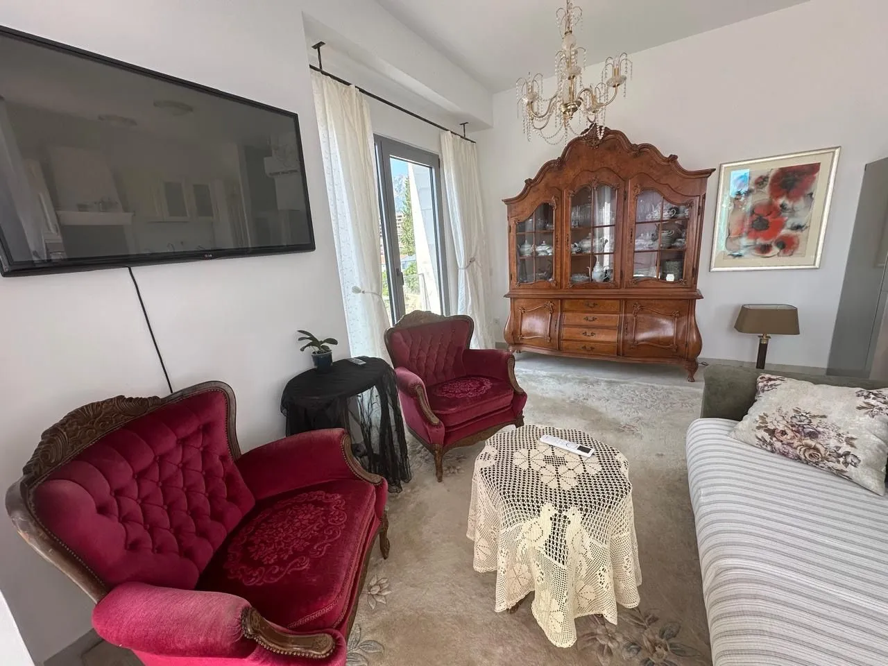 Spacious living room with seating area, traditional furniture and wall-mounted TV.