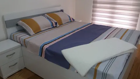 Svijetla spavaća soba sa namještenim bračnim krevetom i noćnim ormarićem. - image 4