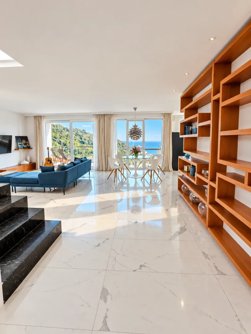 Spacious living room with a dining area, a large wooden bookshelf, and a sea view.
