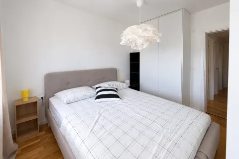 Svjetla spavaća soba sa bračnim krevetom, bijelim ormarom i drvenim podom. - image 8