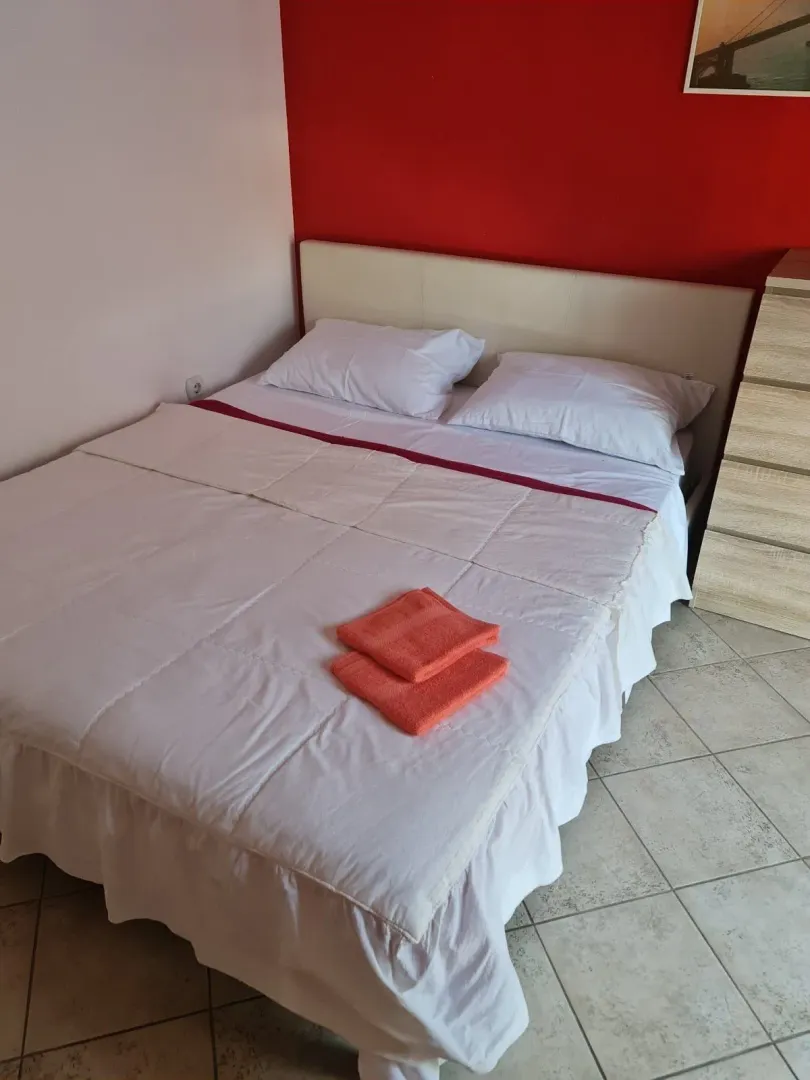 Spavaća soba sa bračnim krevetom i crvenim zidom.