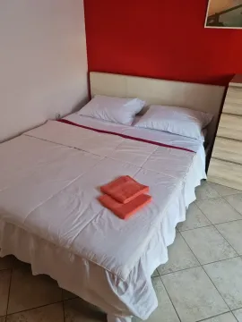 Spavaća soba sa bračnim krevetom i crvenim zidom. - image 14
