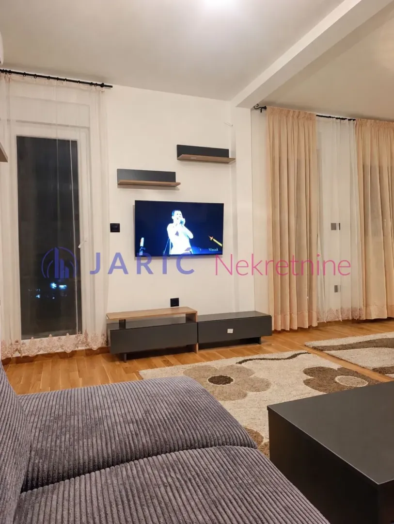 Living room with sofa, TV and curtains.