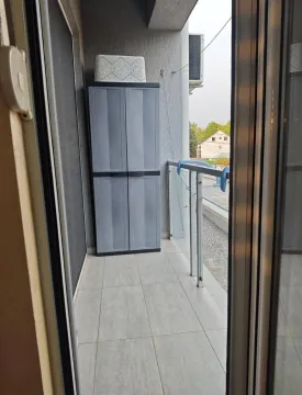 Pogled na manji popločani balkon sa plastičnim ormarom i staklenom ogradom. - image 4