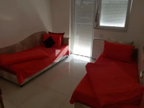 Spavaća soba sa dva kreveta sa crvenim posteljinama i balkonskim vratima. - image 9