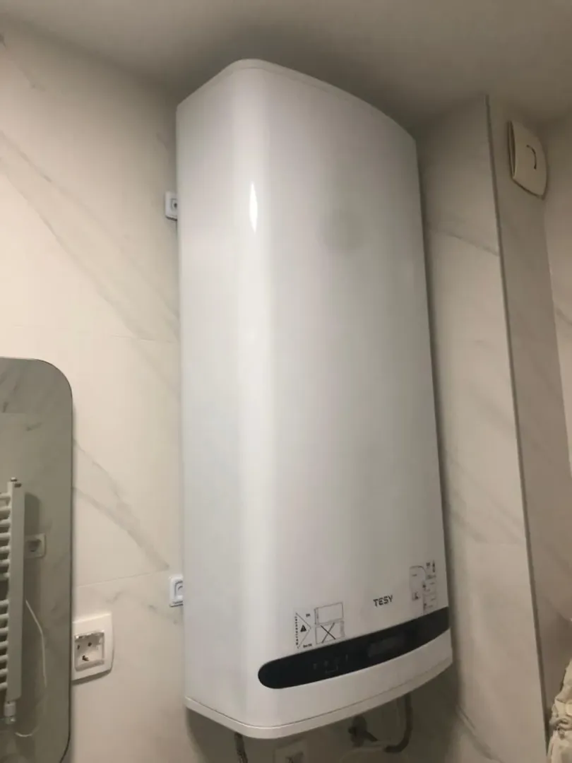 A modern electric water heater mounted on a bathroom wall.